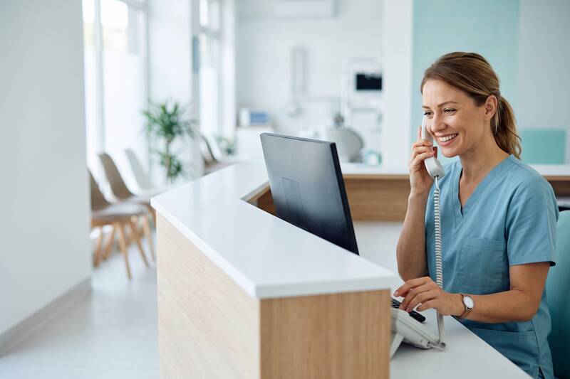 Receptionist at a dental clinic front desk talking on the phone