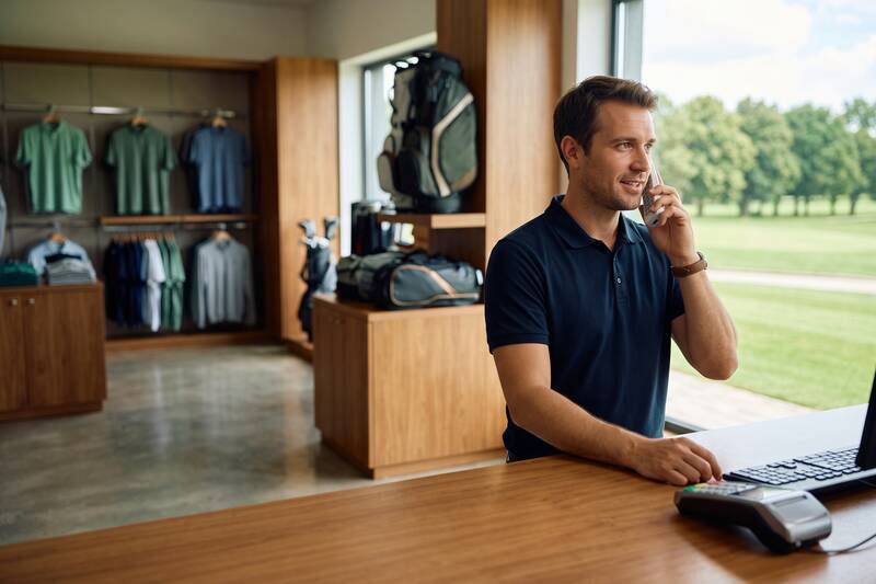 Golf pro shop staff member talking on a cordless phone at the counter